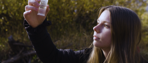 student examining vial outdoors