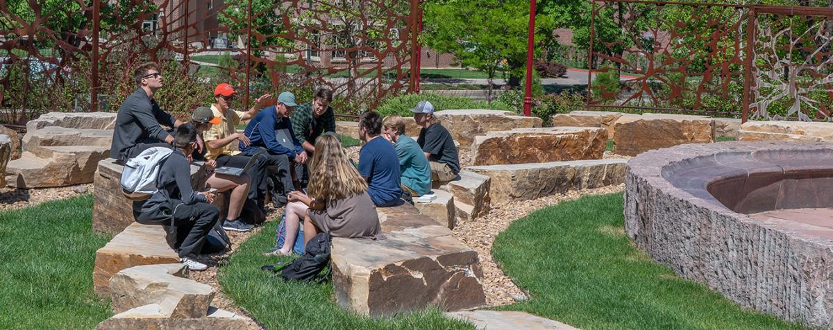 students sitting outside on rocks on campus